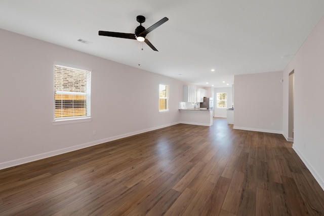 unfurnished living room featuring ceiling fan and dark hardwood / wood-style flooring