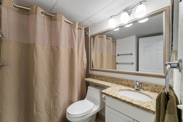 bathroom with vanity, toilet, a shower with shower curtain, and a drop ceiling