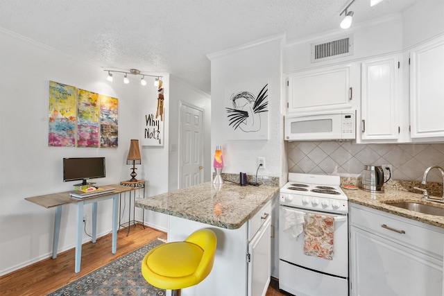 kitchen with hardwood / wood-style floors, sink, backsplash, white cabinets, and white appliances