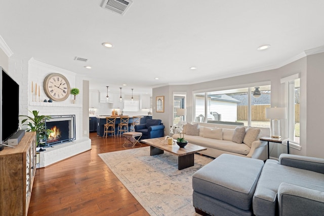 living room with crown molding, wood-type flooring, and a fireplace