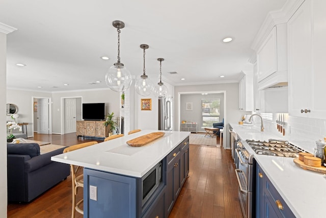 kitchen featuring blue cabinetry, appliances with stainless steel finishes, a center island, white cabinets, and decorative light fixtures