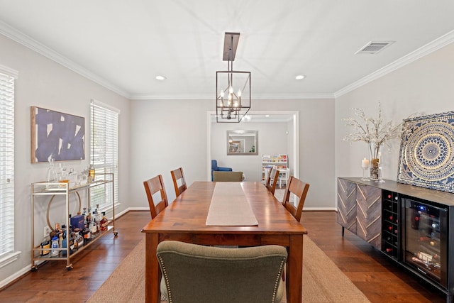 dining room with dark wood-type flooring, wine cooler, ornamental molding, bar area, and a chandelier