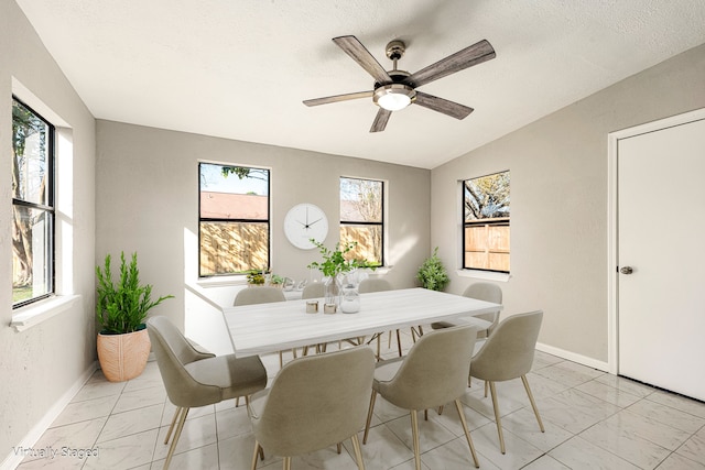 dining area with ceiling fan, vaulted ceiling, and a textured ceiling