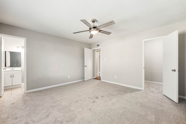 unfurnished bedroom featuring connected bathroom, light colored carpet, and ceiling fan