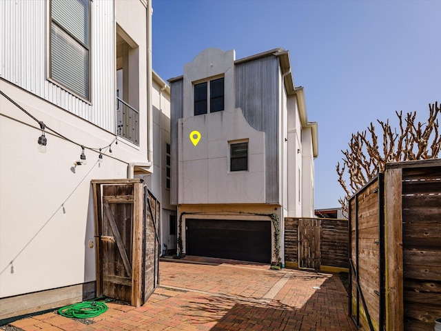 exterior space featuring a garage, decorative driveway, and fence