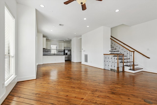 unfurnished living room featuring hardwood / wood-style flooring, stairway, and recessed lighting