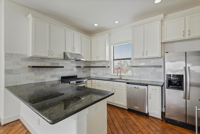 kitchen with dark wood-style flooring, appliances with stainless steel finishes, white cabinets, a sink, and under cabinet range hood