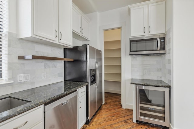 kitchen with beverage cooler, stainless steel appliances, open shelves, and white cabinets