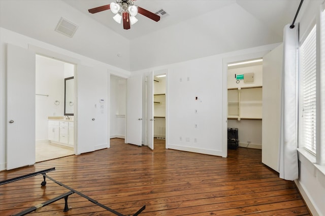 unfurnished bedroom with visible vents, a walk in closet, and hardwood / wood-style flooring