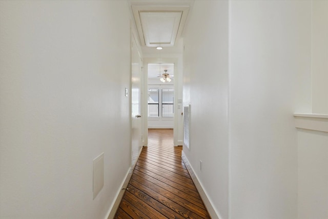 hall with attic access, baseboards, and wood-type flooring