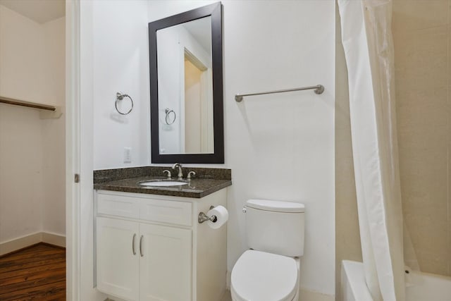 full bathroom featuring toilet, baseboards, wood finished floors, and vanity