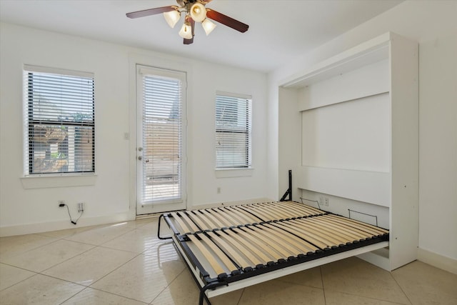 tiled bedroom featuring baseboards, a ceiling fan, and access to exterior