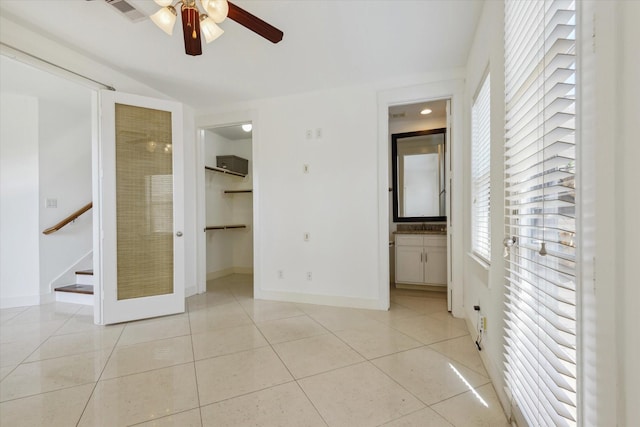 unfurnished bedroom featuring light tile patterned floors, connected bathroom, visible vents, baseboards, and a walk in closet