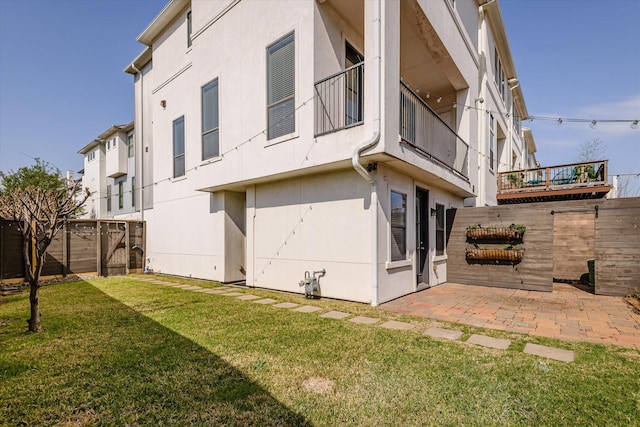 back of property featuring a yard, a patio area, fence, and stucco siding