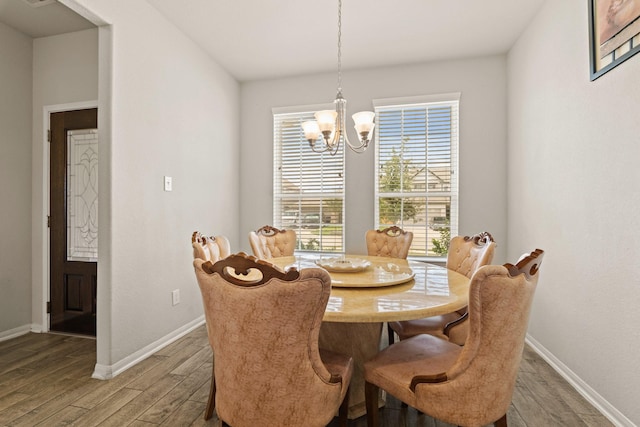 dining area with hardwood / wood-style floors and an inviting chandelier