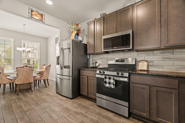 kitchen with pendant lighting, light hardwood / wood-style flooring, dark stone countertops, stainless steel appliances, and decorative backsplash