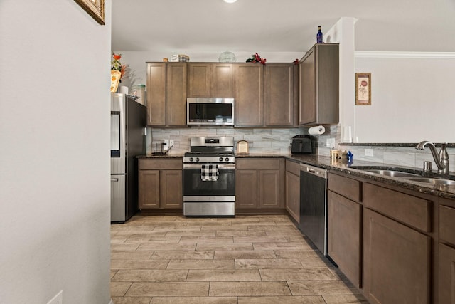 kitchen with sink, backsplash, stainless steel appliances, and dark stone counters