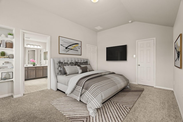 bedroom with light colored carpet, lofted ceiling, and ensuite bathroom