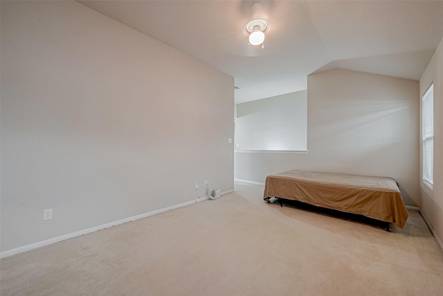 unfurnished bedroom with vaulted ceiling, light colored carpet, and ceiling fan