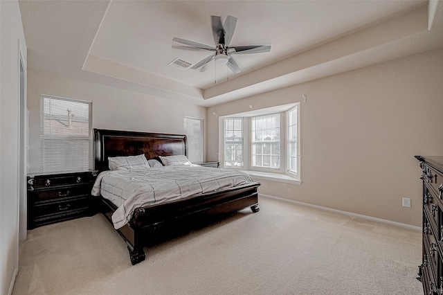 carpeted bedroom featuring a tray ceiling and ceiling fan