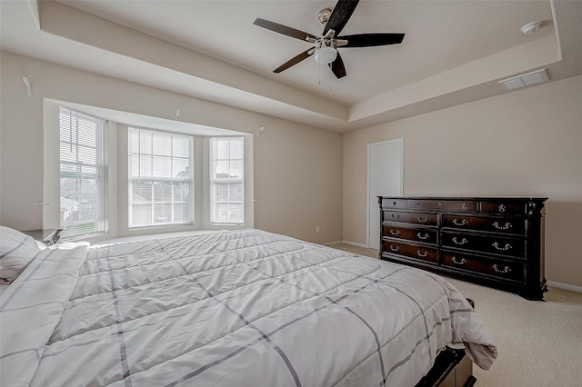 carpeted bedroom featuring ceiling fan and a tray ceiling