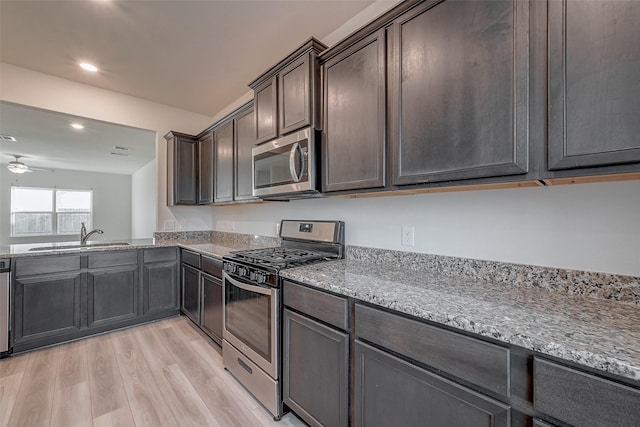 kitchen with sink, ceiling fan, dark brown cabinetry, stainless steel appliances, and light hardwood / wood-style floors