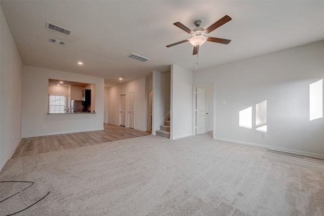 unfurnished living room featuring ceiling fan and light colored carpet