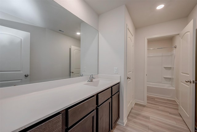 bathroom with hardwood / wood-style flooring, vanity, and tub / shower combination