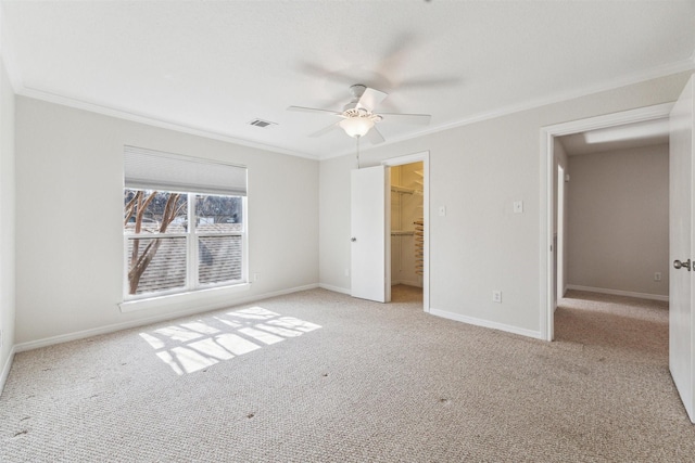 unfurnished bedroom with crown molding, ceiling fan, a walk in closet, light colored carpet, and a closet