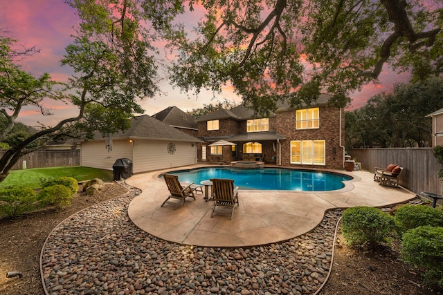 pool at dusk with area for grilling and a patio area