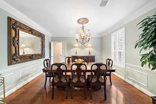 dining space with dark wood-type flooring, crown molding, and an inviting chandelier