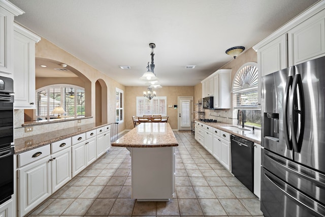 kitchen featuring sink, black appliances, a center island, light stone countertops, and white cabinets