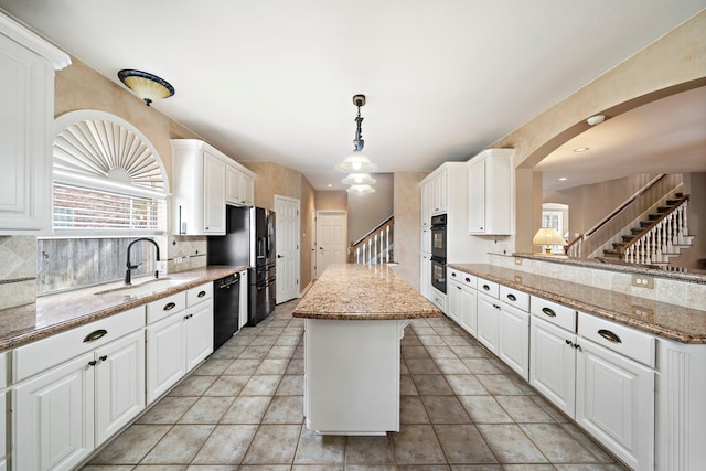 kitchen with pendant lighting, white cabinetry, sink, a center island, and black appliances