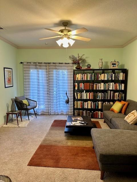 sitting room with ceiling fan, ornamental molding, a textured ceiling, and carpet flooring