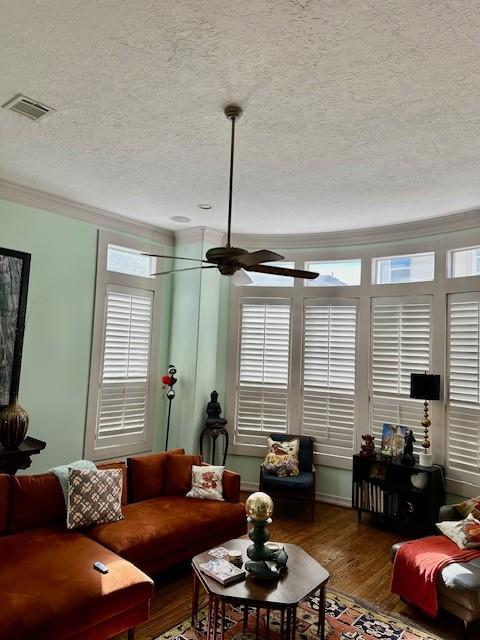 living room featuring hardwood / wood-style flooring, crown molding, a textured ceiling, and ceiling fan