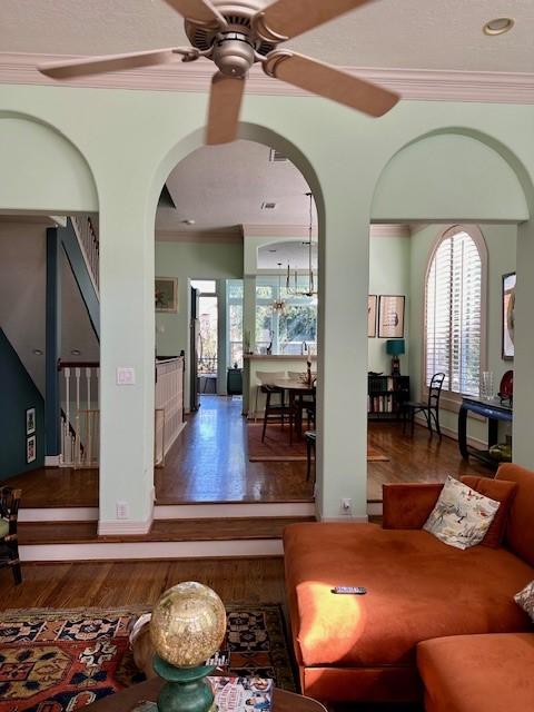 living room featuring crown molding, dark wood-type flooring, and ceiling fan