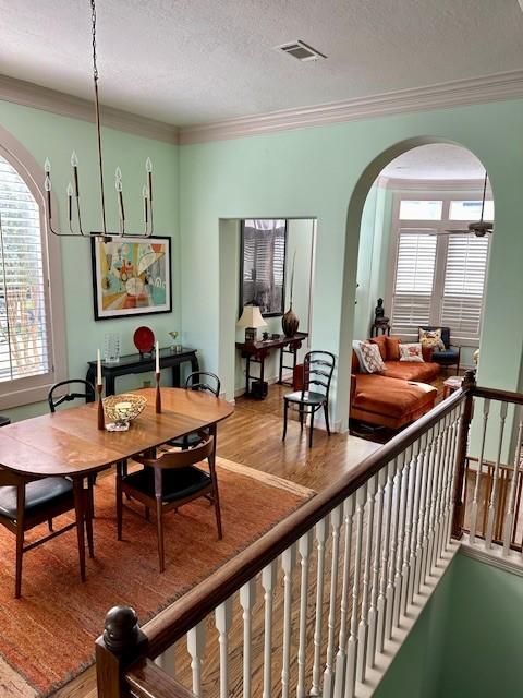 dining room featuring hardwood / wood-style floors, ornamental molding, and a textured ceiling