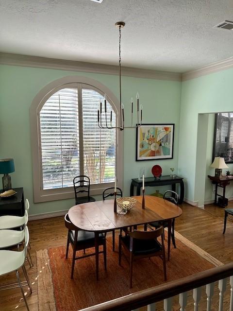 dining area featuring ornamental molding, hardwood / wood-style floors, and a textured ceiling