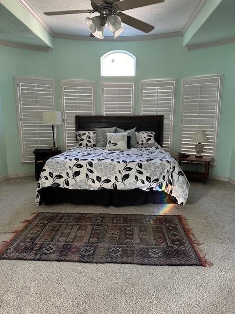 carpeted bedroom with ornamental molding, ceiling fan, and a textured ceiling