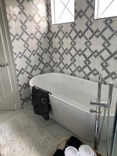 bathroom with a tub to relax in and concrete flooring