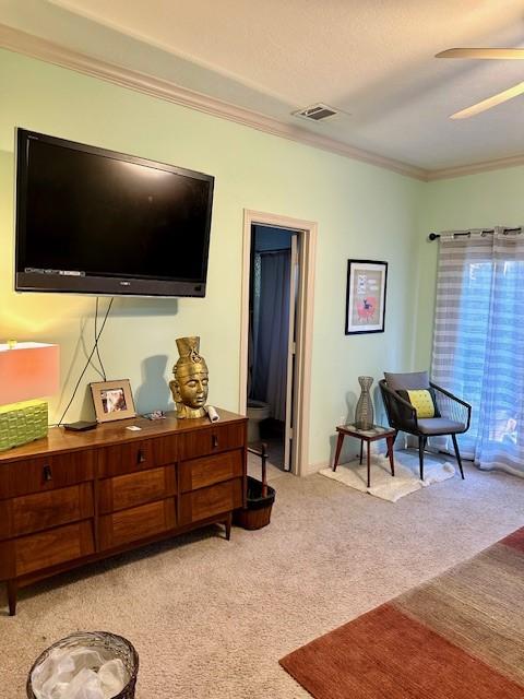 living room with crown molding, light colored carpet, and ceiling fan