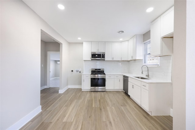 kitchen featuring tasteful backsplash, stainless steel appliances, sink, and white cabinets