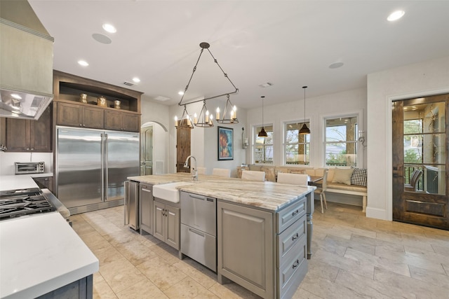 kitchen featuring sink, gray cabinetry, decorative light fixtures, an island with sink, and stainless steel appliances