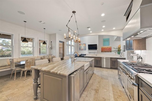 kitchen with pendant lighting, sink, light stone countertops, and a spacious island