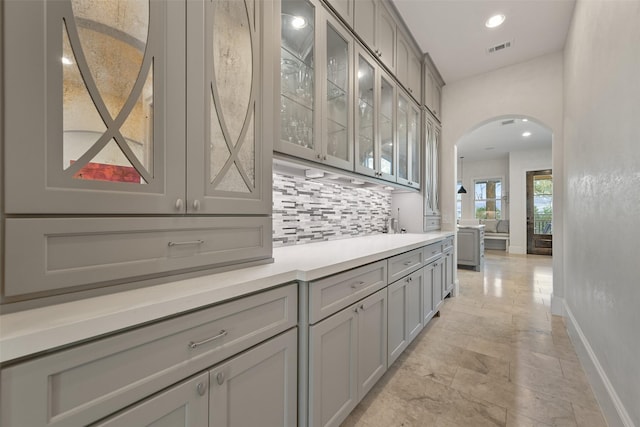 bar featuring gray cabinets and decorative backsplash