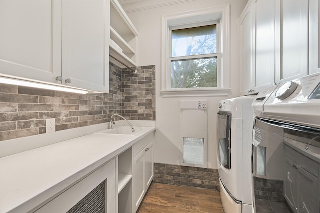 clothes washing area featuring cabinets, sink, dark wood-type flooring, and washer and clothes dryer