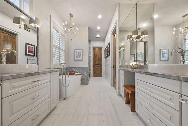 bathroom with vanity, a bath, a chandelier, and tile walls