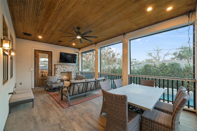 sunroom with ceiling fan, wooden ceiling, and an outdoor stone fireplace