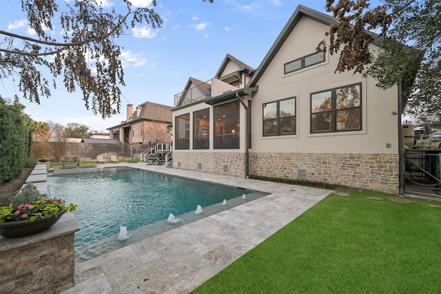 view of swimming pool featuring pool water feature, a yard, and a sunroom