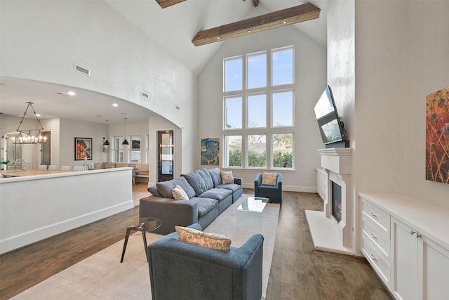 living room with an inviting chandelier, beam ceiling, dark wood-type flooring, and high vaulted ceiling